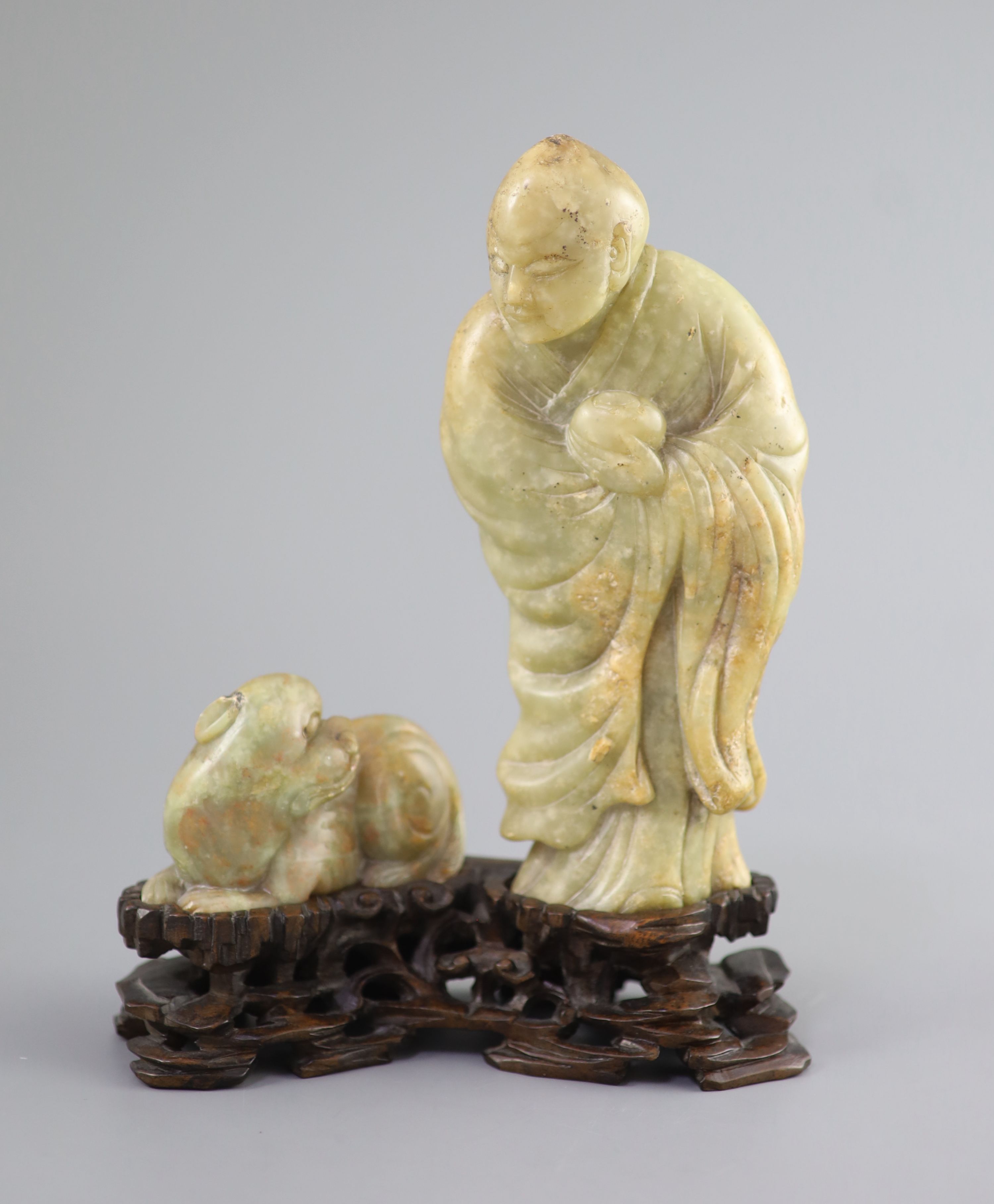 A Chinese soapstone group of a luohan and a lion dog, possibly 17th/18th century, 22.5 cm height including card wood stand